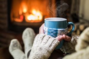 Warming and relaxing near fireplace with a cup of hot drink.